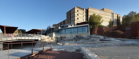 A modern building with a glass facade and a stone pathway leading to a covered area.