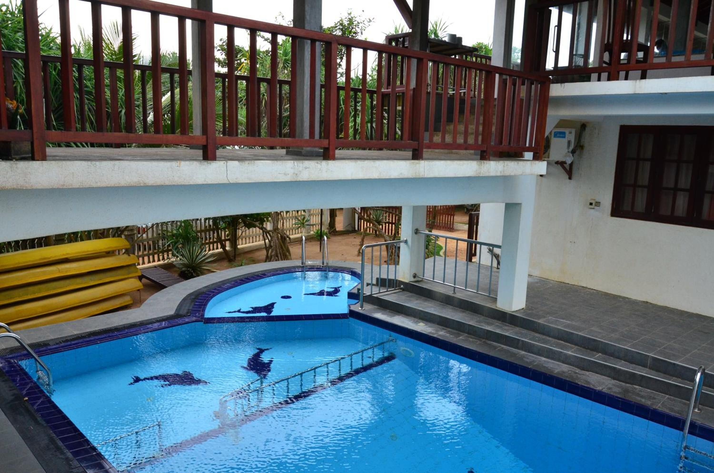 An indoor swimming pool with a wooden deck and a view of the surrounding greenery.