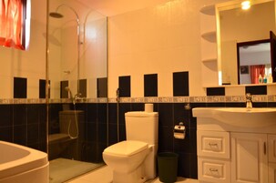 Un baño con ducha envuelta en vidrio, inodoro, lavabo y espejo sobre el lavabo.