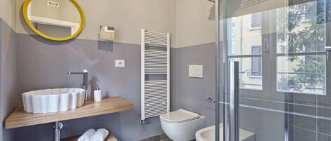 A modern bathroom with a round mirror, a sink, a toilet, and a shower area.
