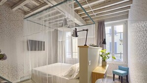 A bedroom with a bed, bedside table, chair, and a window with curtains. - Hotel Torino (Parma)