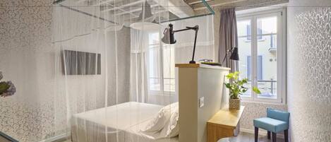Una camera da letto con un letto, un comodino, una sedia e una finestra con tende.
