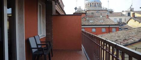 A balcony with two chairs, a tiled floor, and a view of a domed building in the background.