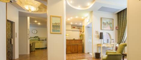 A spacious living room with a green sofa, a wooden coffee table, and a dining area with a wooden cabinet and a lamp.