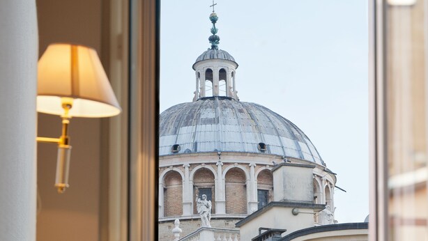 A hotel room with a view of a historic building with a dome and bell tower. - Hotel Torino (Parma)
