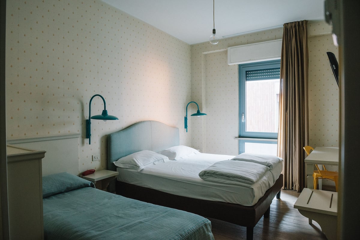 A hotel room with two beds, a desk, and a chair.