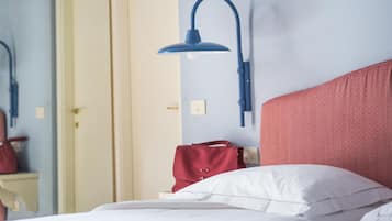 Una habitación de hotel con una cama, cabecera roja, lámpara de pared azul y una puerta al fondo.