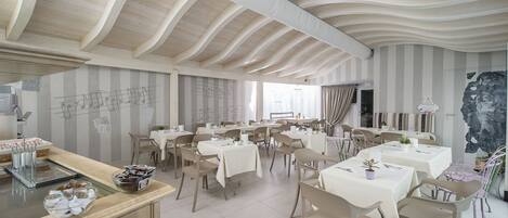 A restaurant with a modern interior, featuring wooden ceiling beams and striped walls. Tables are set with white tablecloths and chairs.