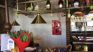 A bar area with a red heart-shaped planter, a bowl of chocolates, a basket of colorful candies, and a display of various bottles and glasses. - De Koningsherberg (Anloo)