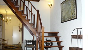 A wooden staircase with a chandelier, a map on the wall, and a rustic chair. - De Koningsherberg (Anloo)