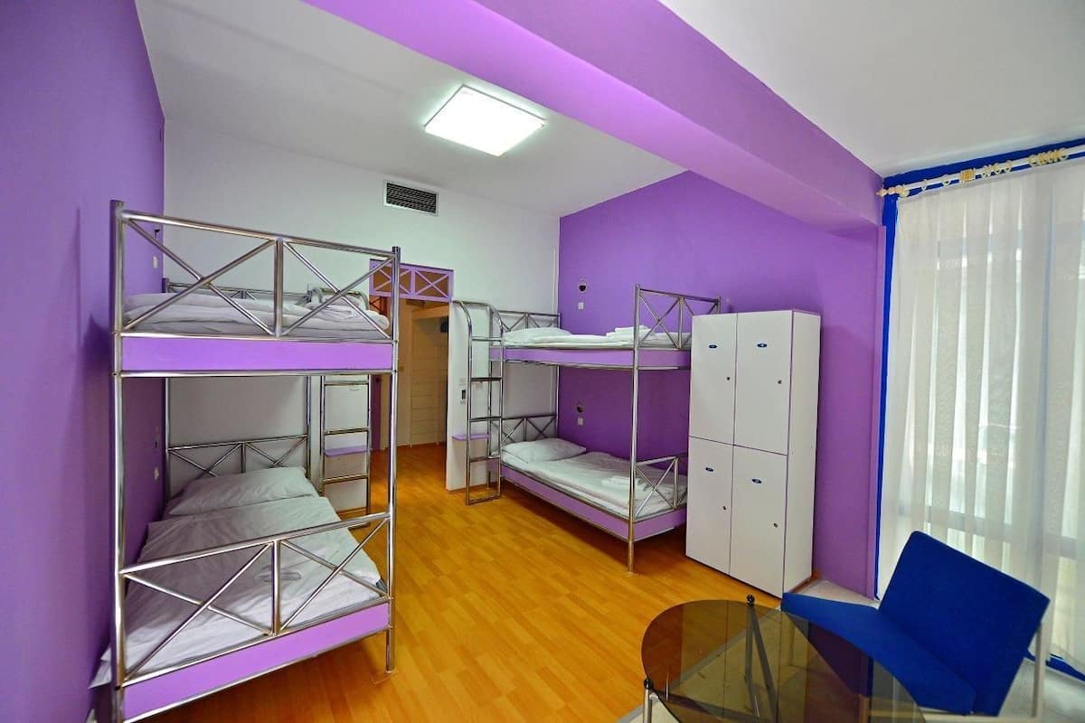 A dormitory room with bunk beds, a small table, and a blue chair.