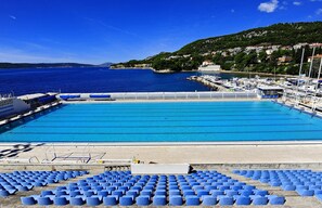 A swimming pool with blue water, surrounded by blue chairs and a dock with boats. - Jadran-Zvončac Accommodations - Hostel (Split)