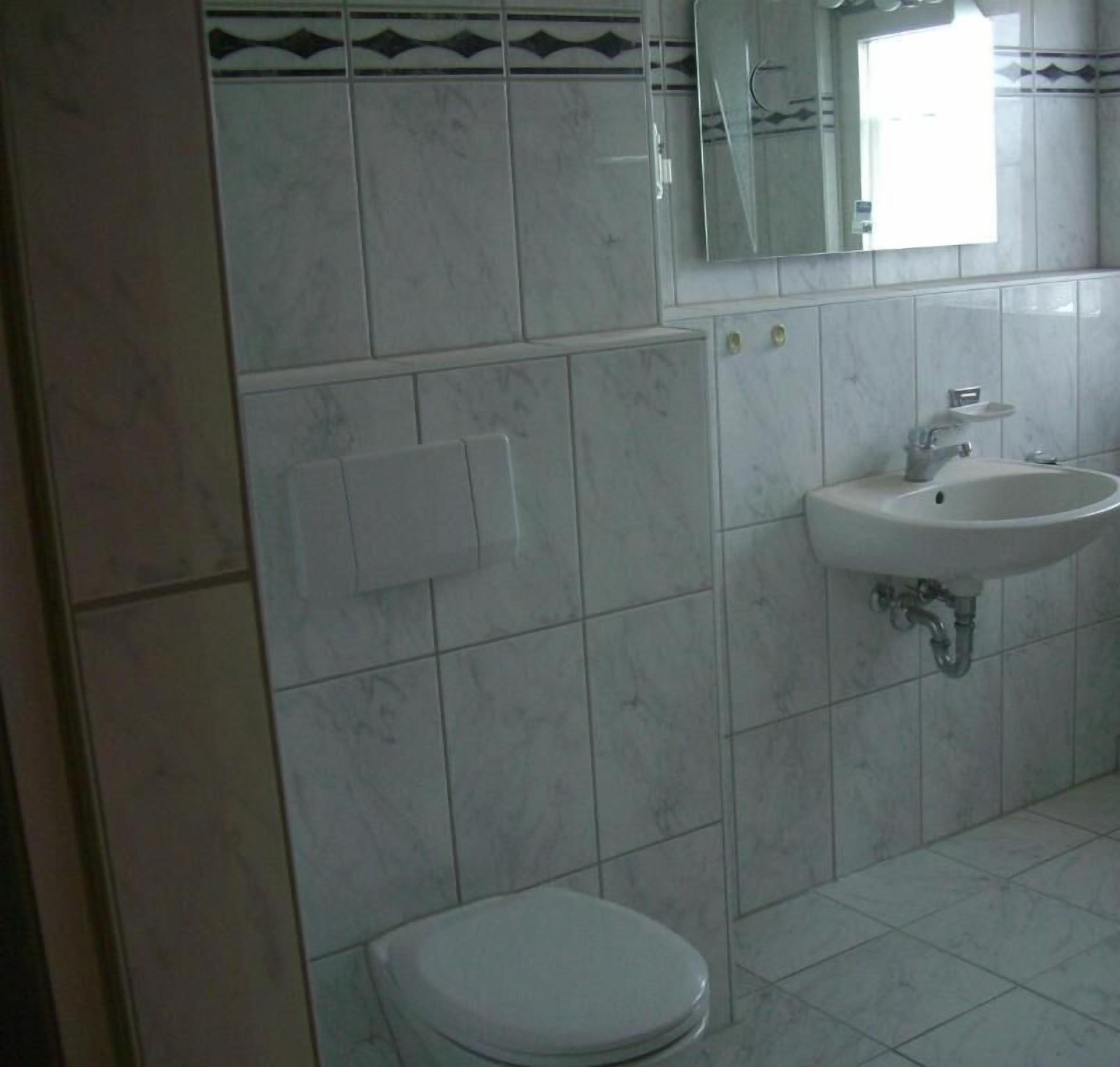 A bathroom with a toilet, sink, and mirror.