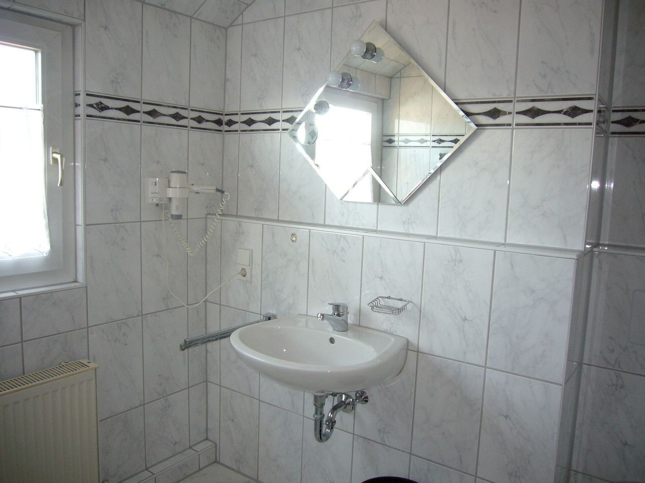 A bathroom with a white sink, a mirror, and a shower.