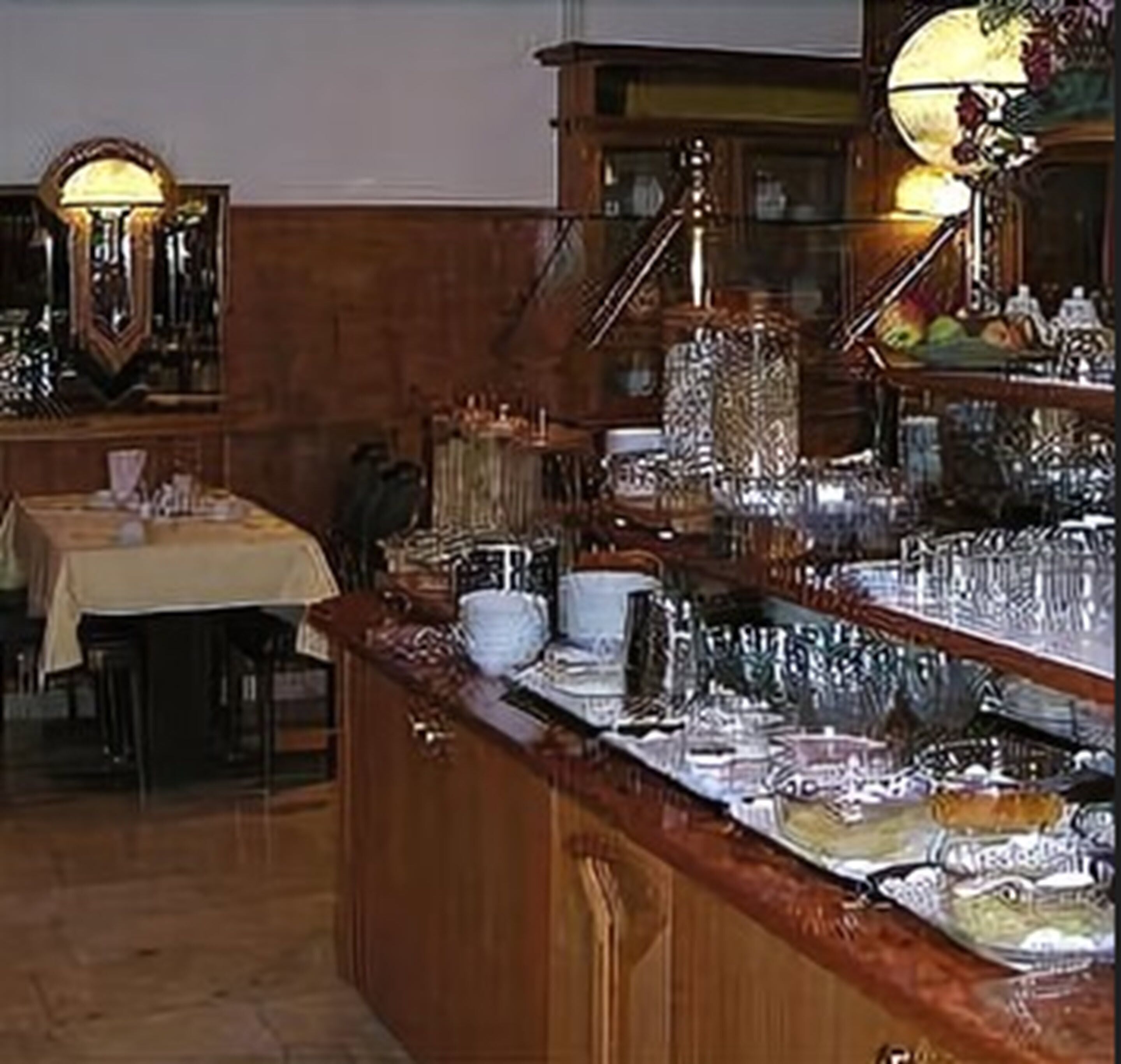 Uma área de buffet com diversos pratos, um espaço de bar com espelho e uma mesa com toalha.