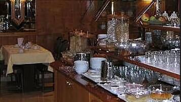 Uma área de buffet com diversos pratos, um espaço de bar com espelho e uma mesa com toalha.