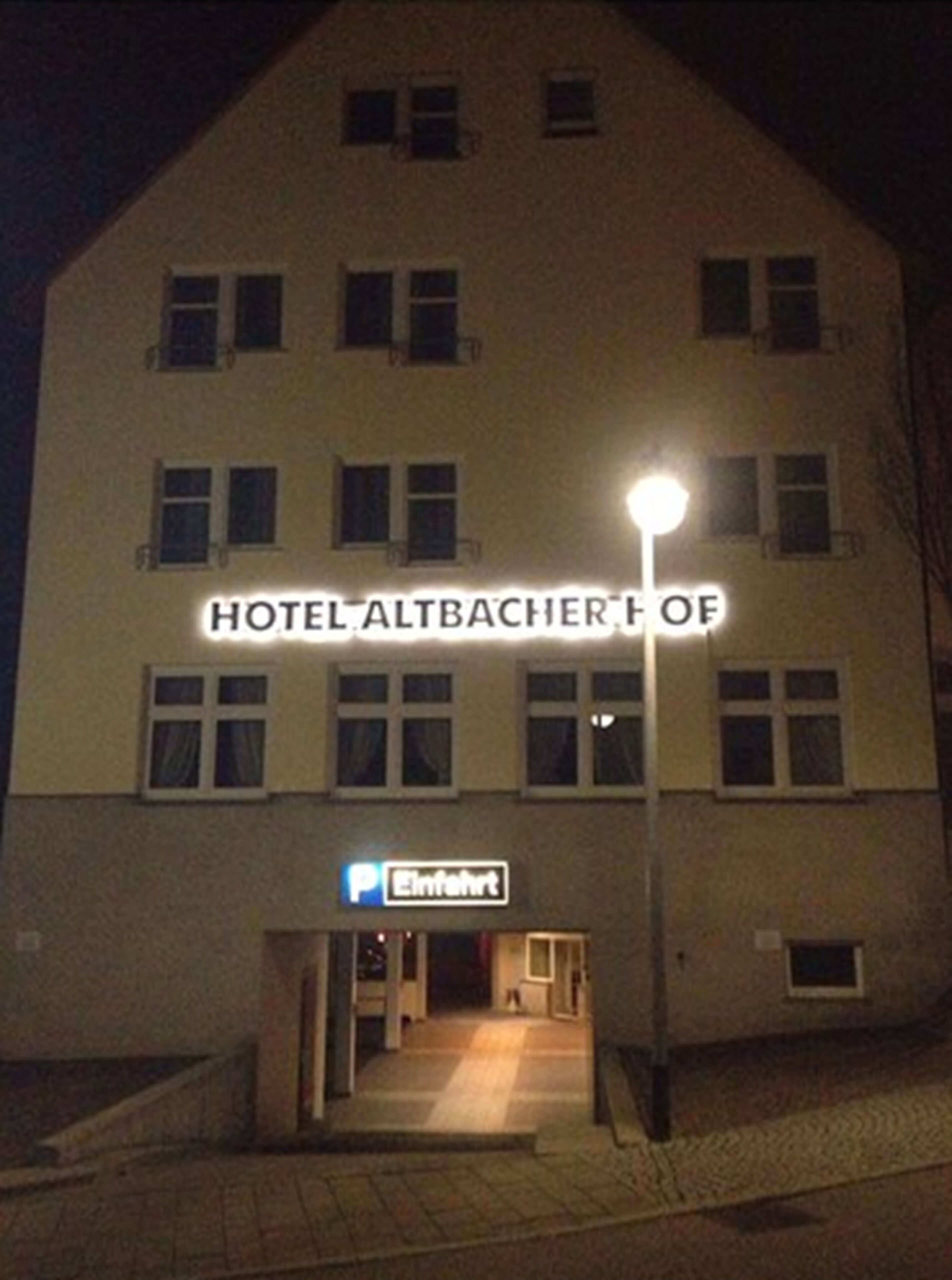 A building with a sign reading "HOTEL ALTBACHER OF" and a parking sign below.