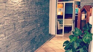 A hallway with a stone wall, a tiled floor, and a potted plant.