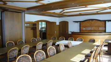 A conference room with a long table and chairs, wooden paneling, and a counter with a display.