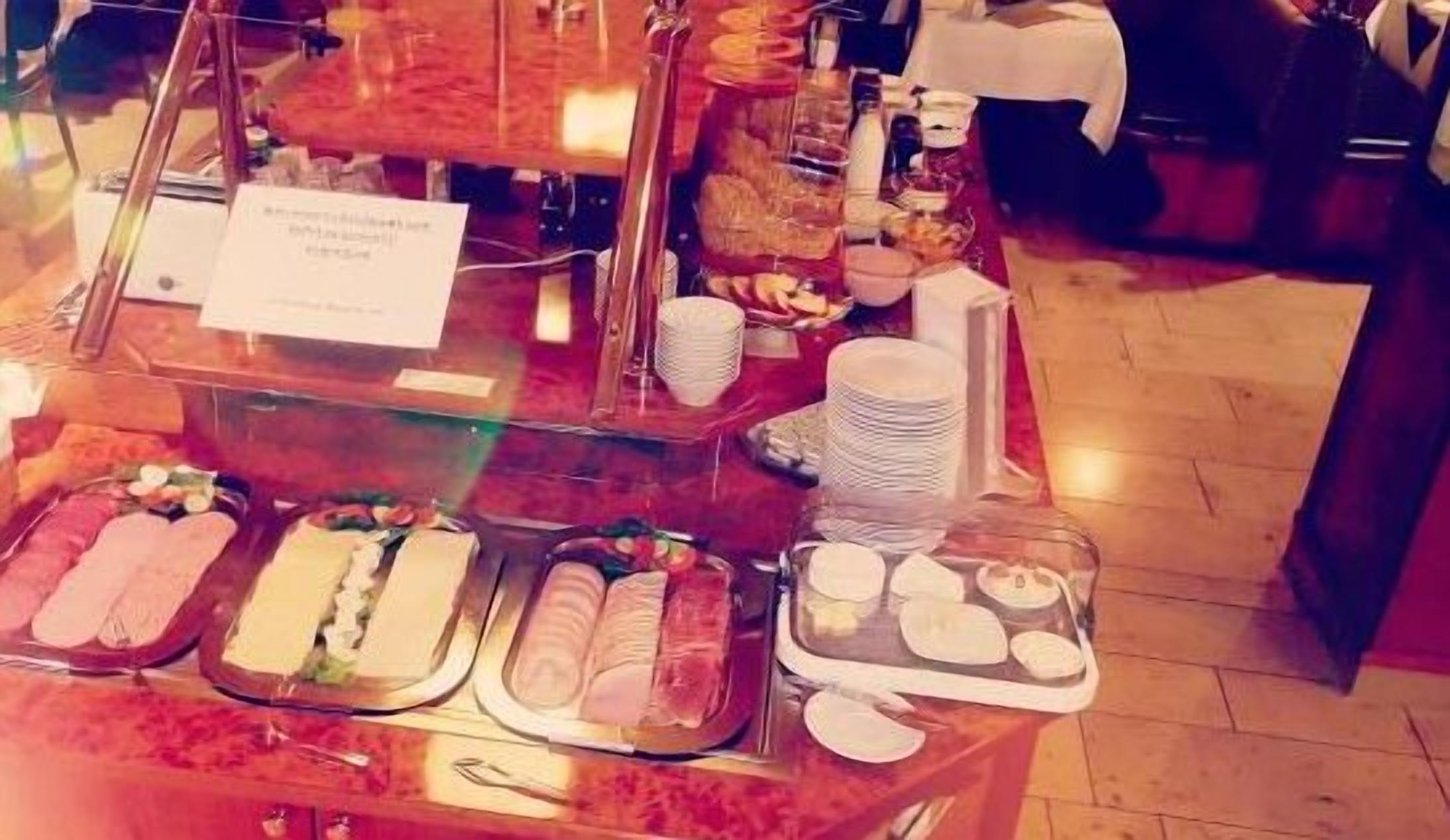 A buffet with various food items and a sign indicating the breakfast menu.