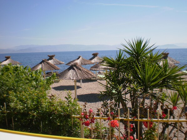 Une plage avec des parasols en chaume et une vue sur la mer.