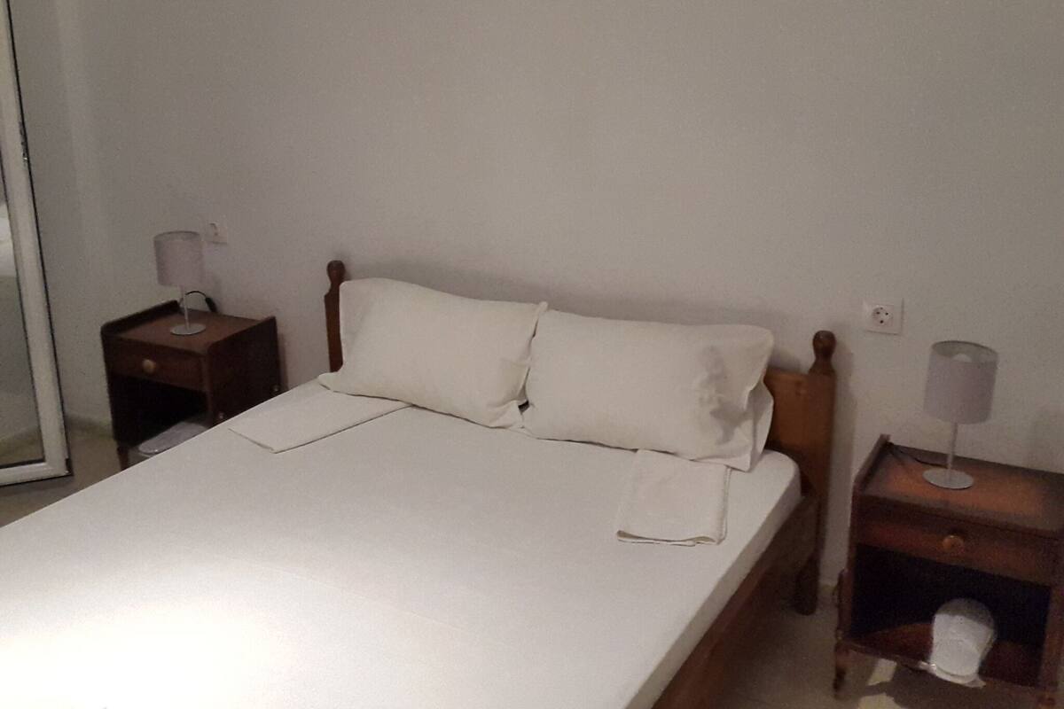 A simple, clean room with a single bed, two bedside tables, and a nightstand.