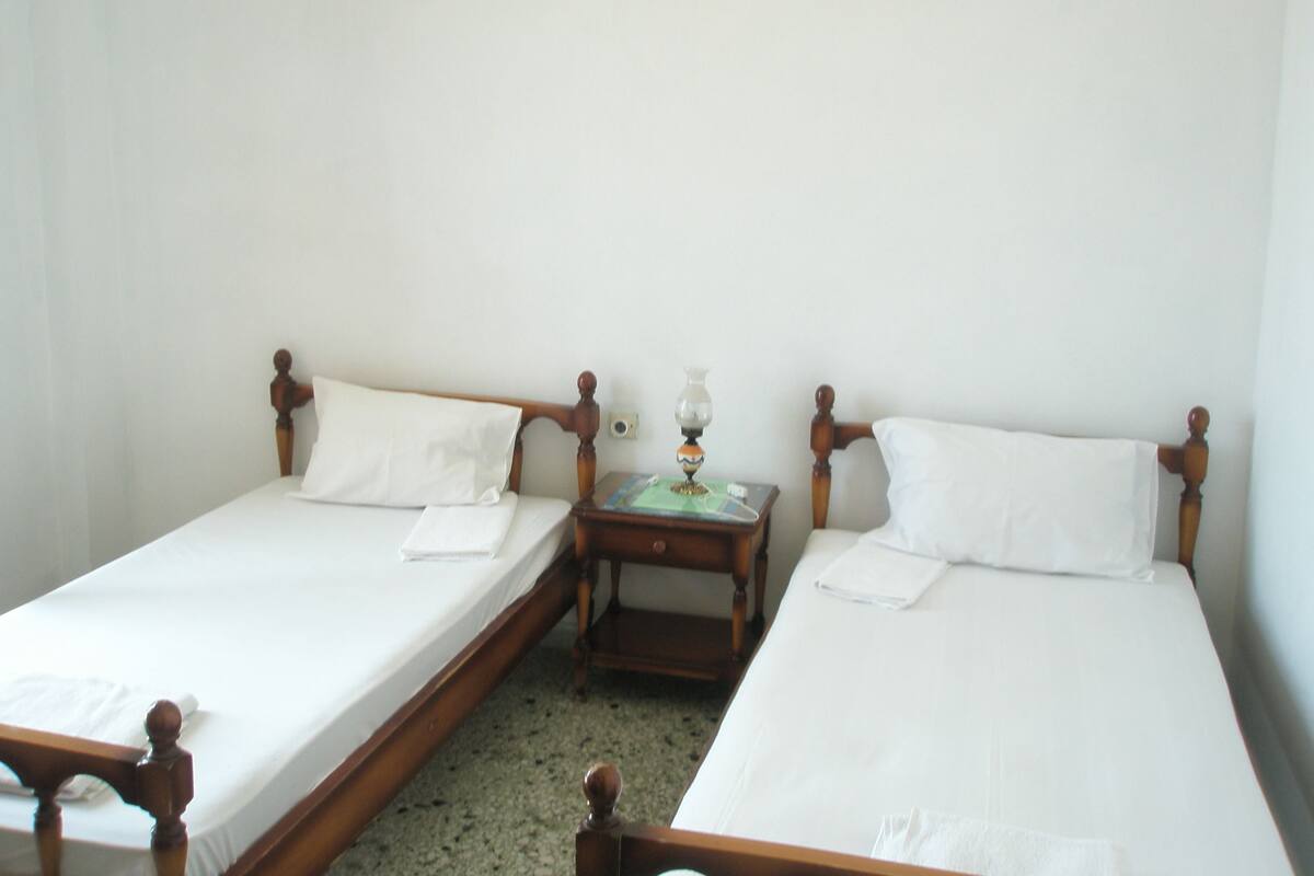 Two single beds with wooden headboards in a room with white walls.