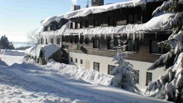 A multi-story building with snow-covered roofs and a snowy landscape. - Hotel Diana (Benecko)