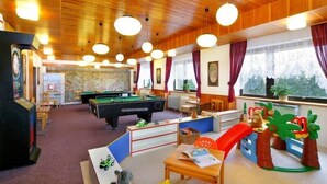 A cozy indoor space with a pool table, children's play area, and a view of the outdoors. - Hotel Diana (Benecko)