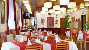 A restaurant with multiple tables set for dining, featuring red tablecloths and white napkins. - Hotel Diana (Benecko)