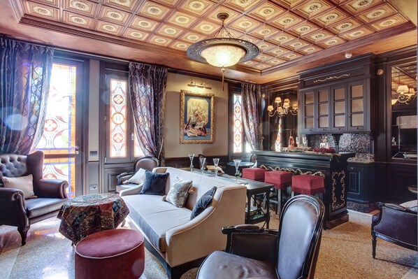 A luxurious hotel room with a large bed, a dining table set for four, a bar area, and a chandelier. - Hotel Moresco (Venice)