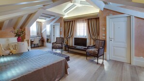A spacious bedroom with a large bed, a TV, and two chairs. - Hotel Moresco (Venice)