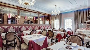 A dining area with tables set for service, a chandelier, and a view of the kitchen through a glass partition. - Hotel Moresco (Venice)