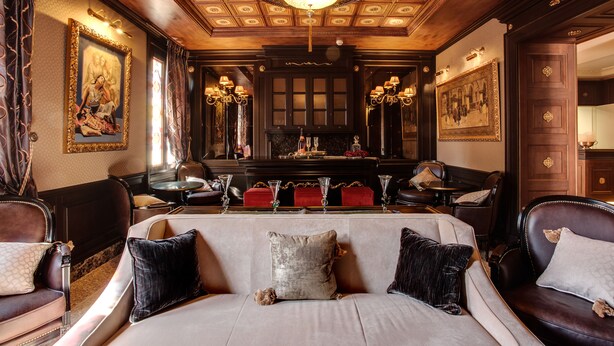 A luxurious room with a large sofa, two armchairs, a fireplace, and ornate ceiling details. - Hotel Moresco (Venice)