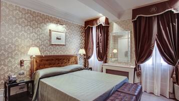 Una habitación de hotel con una cama grande, una mesita de noche con lámpara, un espejo y un banco.
