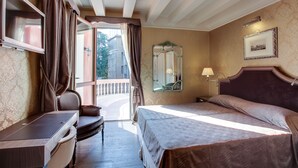 A hotel room with a bed, a desk, a chair, a mirror, and a window with curtains. - Hotel Moresco (Venice)