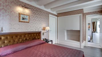 Une chambre d’hôtel avec un grand lit, une tête de lit, une table de chevet avec une lampe, un tableau encadré au mur et une armoire.