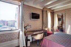 A hotel room with a bed, desk, chair, TV, and a view of the city. - Hotel Moresco (Venice)