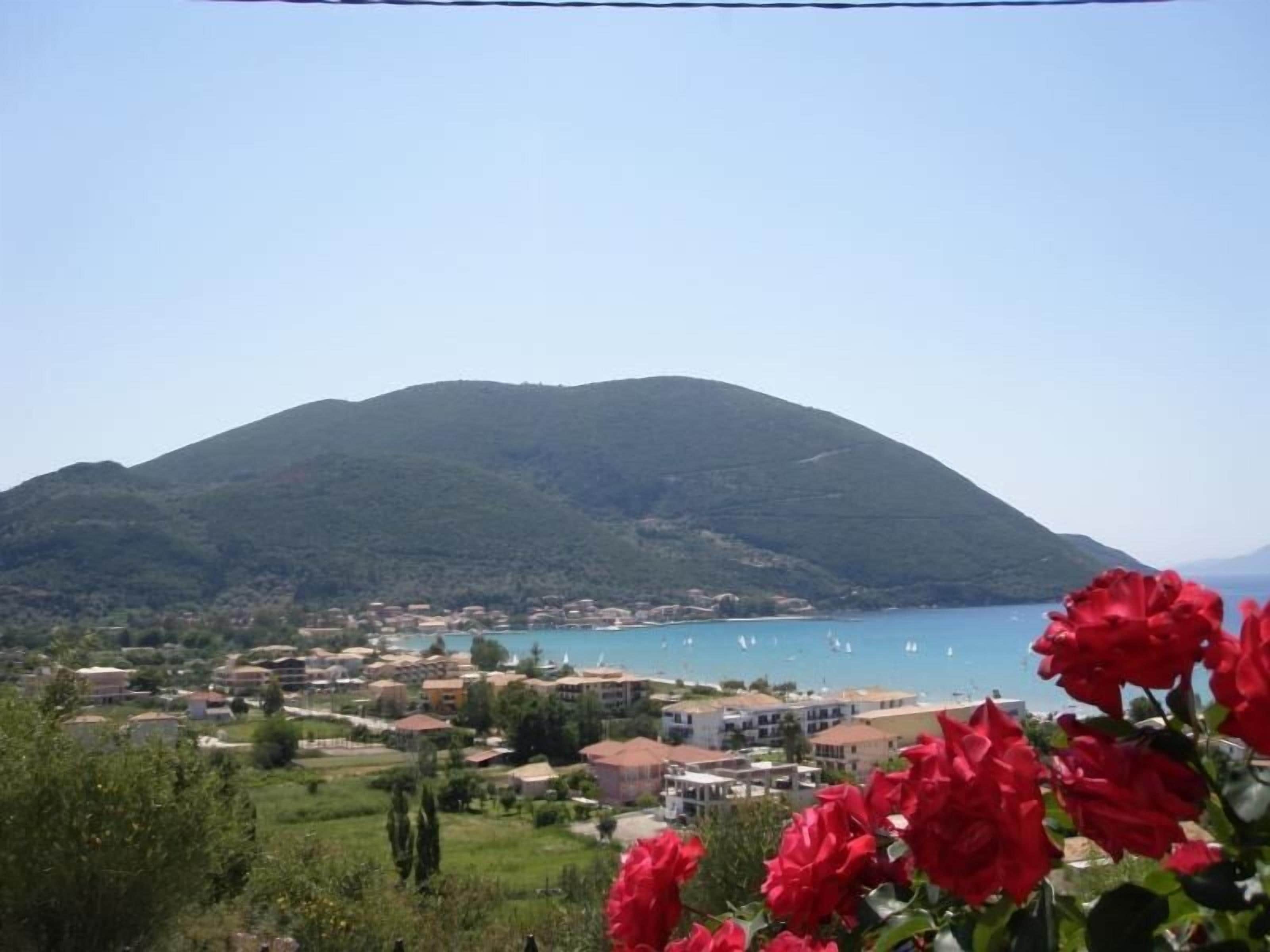 Eine Küstenstadt mit einem Berg im Hintergrund, Häuser und einem klaren, blauen Meer.