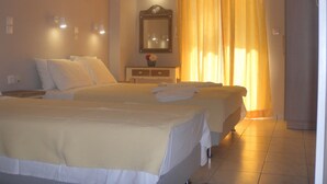 Une chambre d’hôtel avec deux lits, une table de chevet, un miroir et une fenêtre avec des rideaux.