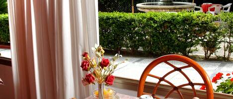 A breakfast table set with plates, cups, and a vase of flowers.