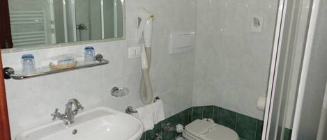 A bathroom with a sink, bidet, toilet, and a shower area.