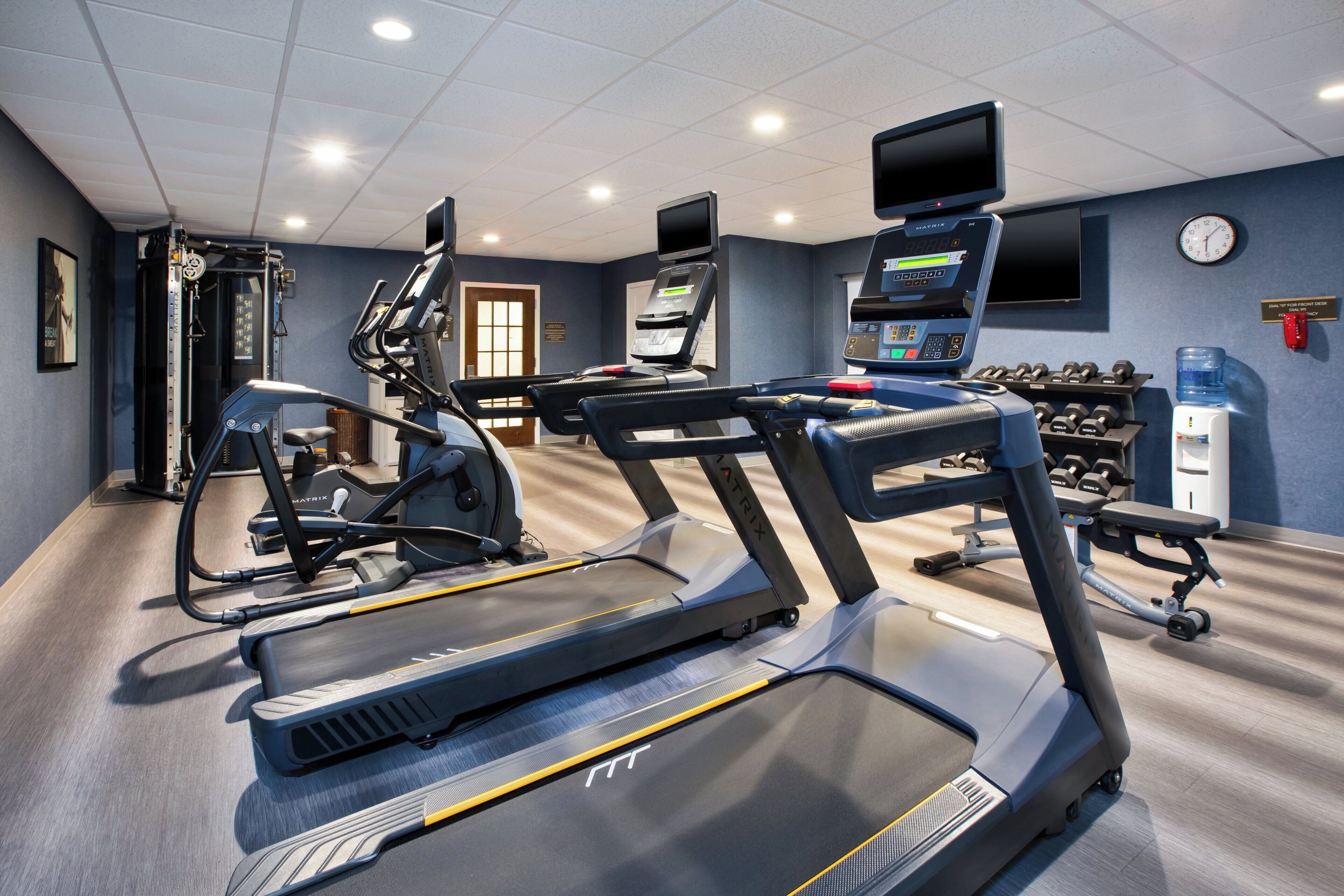Un gimnasio con cintas de correr, elípticas y equipo de levantamiento de pesas.