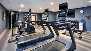 Ein Fitnessstudio mit Laufbändern, Crosstrainern und Gewichten.