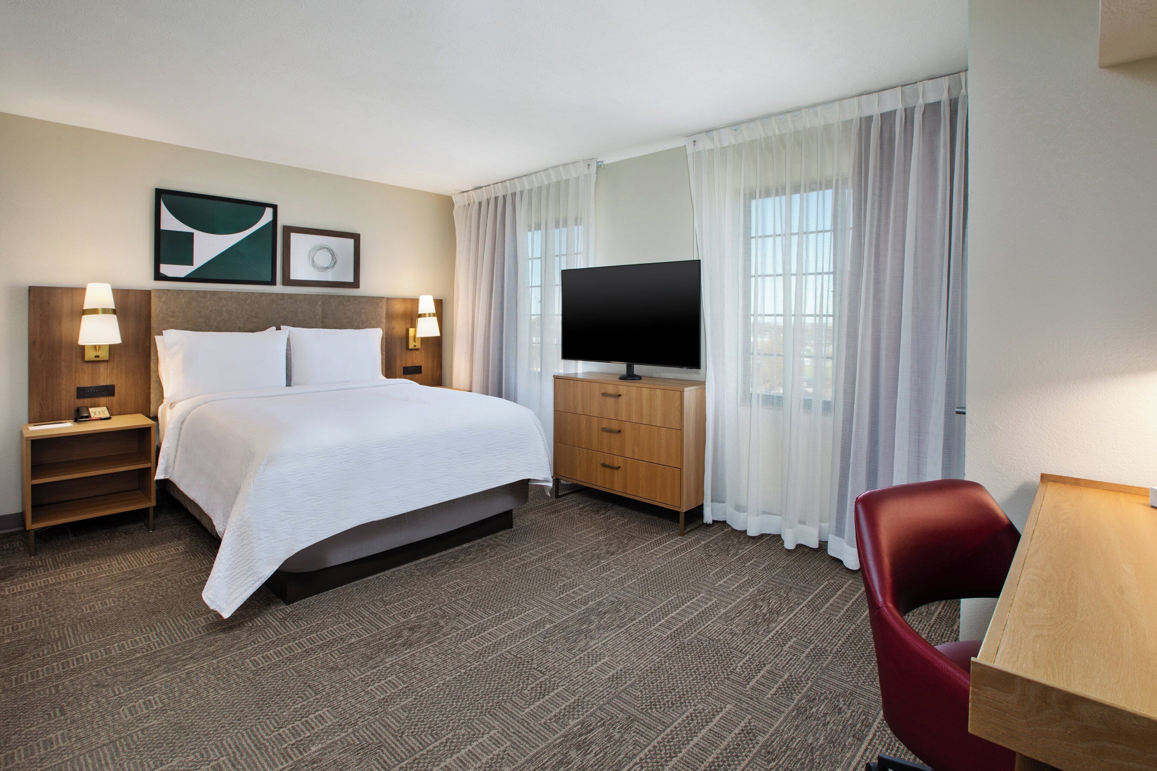 Una habitación de hotel con una cama grande, televisión, escritorio y una silla.
