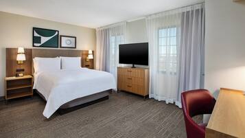 Una habitación de hotel con una cama grande, televisión, escritorio y una silla.