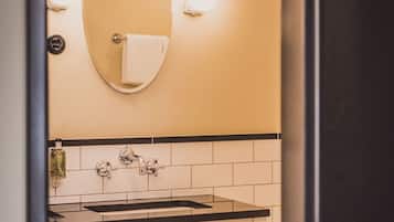 Un baño con un lavabo blanco, un espejo y una toalla colgada en la pared.