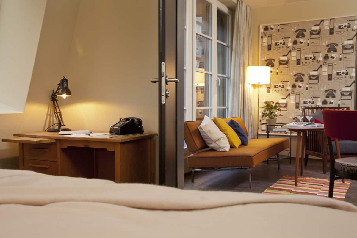 Een hotelkamer met een bureau, een bed, een bank en een stoel.