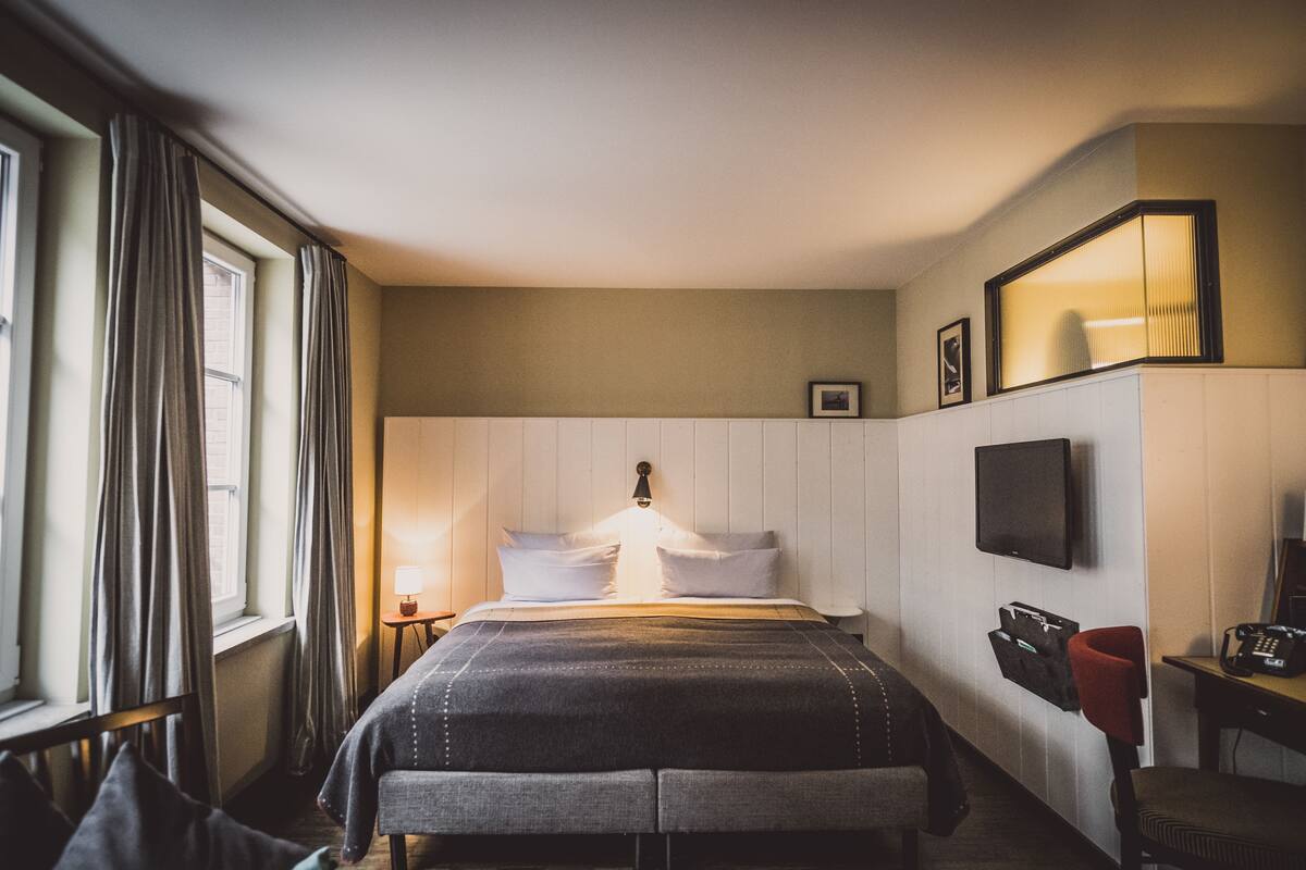 Een hotelkamer met een bed, een televisie, een bureau en een stoel.