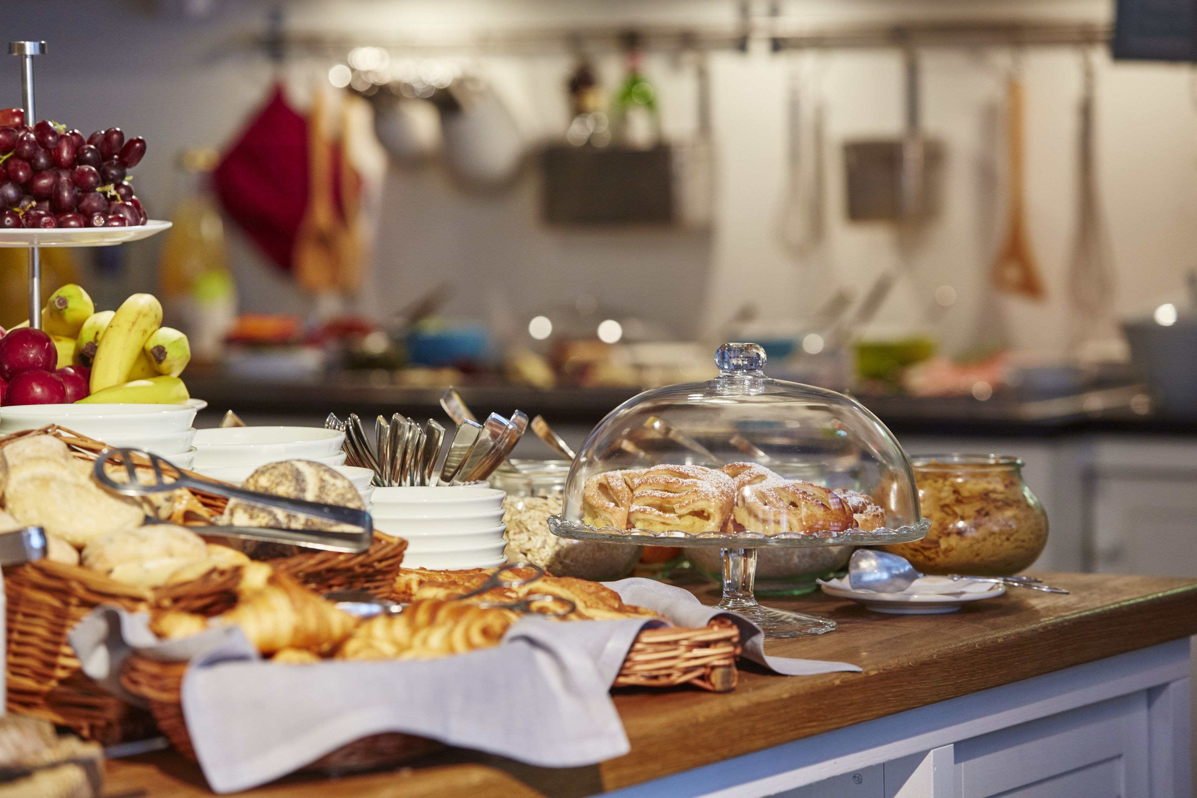A buffet with various food items including fruits, pastries, and bread.